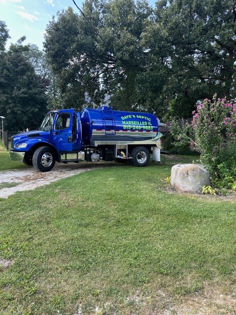 A blue tanker truck is parked in a grassy field.