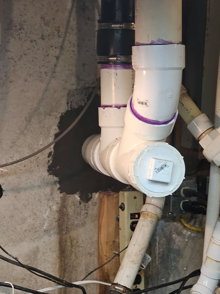 A bunch of white pipes are connected to a wall.