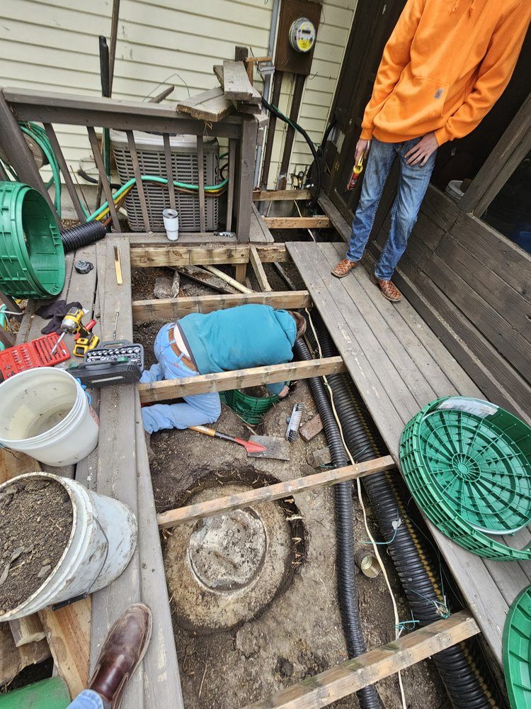 A man is laying on the ground under a deck.