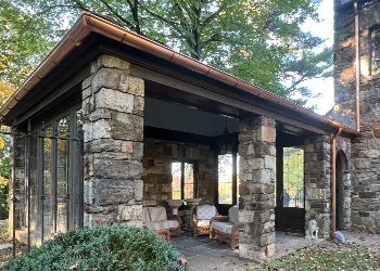 a stone pavilion with a copper gutter and a dog standing in front of it .