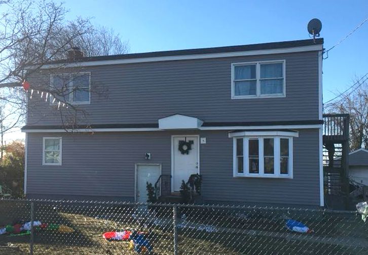 a gray house with a chain link fence around it