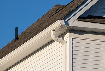 a white house with a brown roof and a white gutter