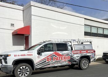 a white truck is parked in front of a white building .