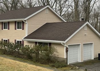 a house with two garage doors and a brown roof .