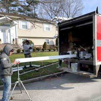 a man is standing next to a red and white truck in front of a house .