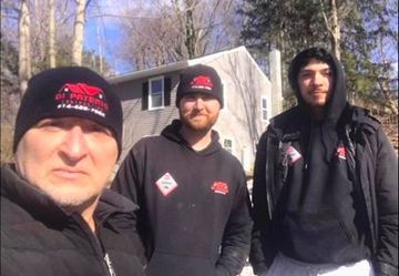 three men are posing for a picture in front of a house .