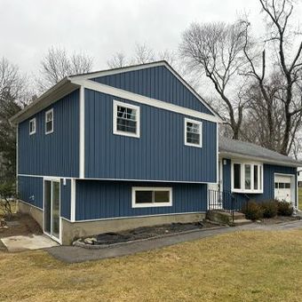 the front of a house with a porch and a lot of windows .