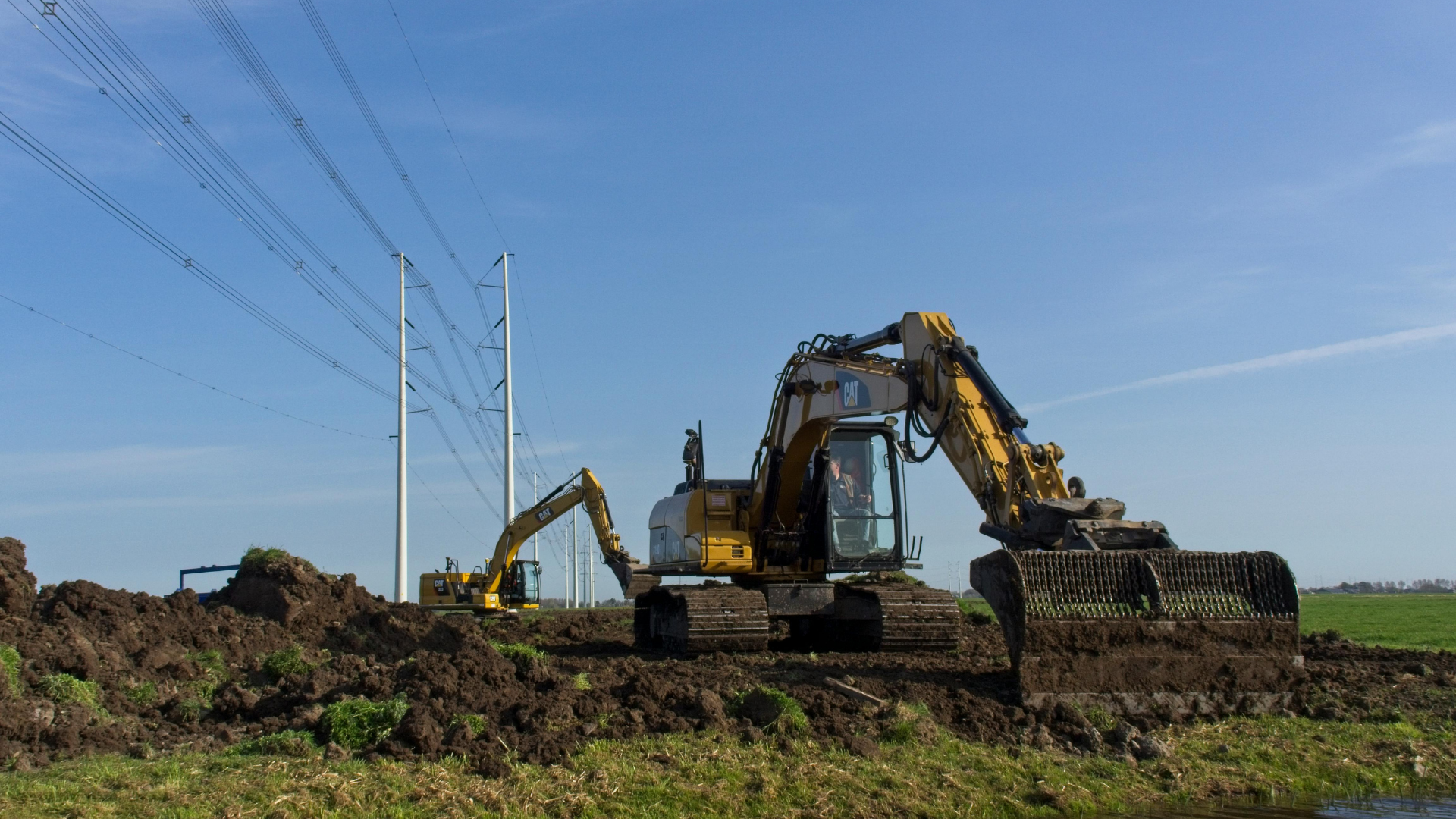Excavators digging earth at a construction site under a clear blue sky