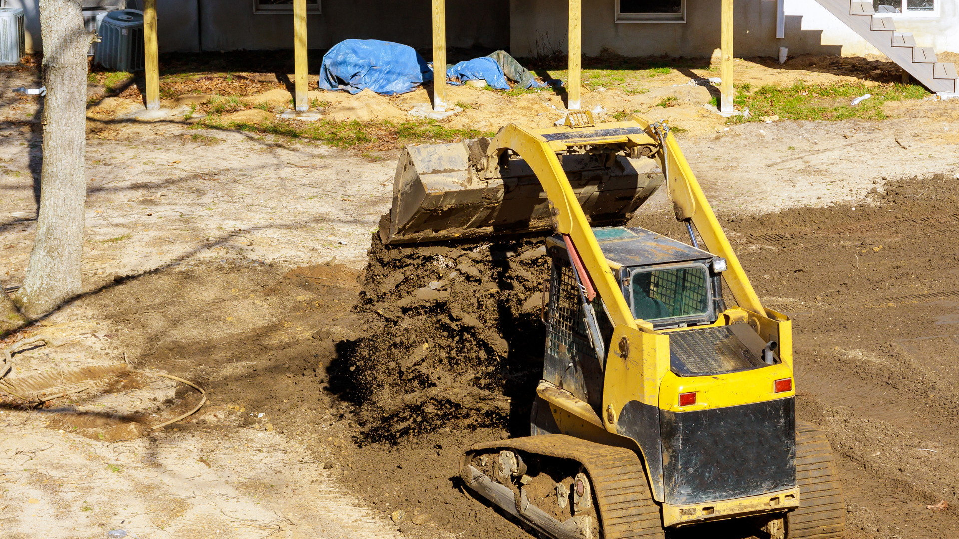 Orange excavators clearing rubble at a construction site with dust and debris