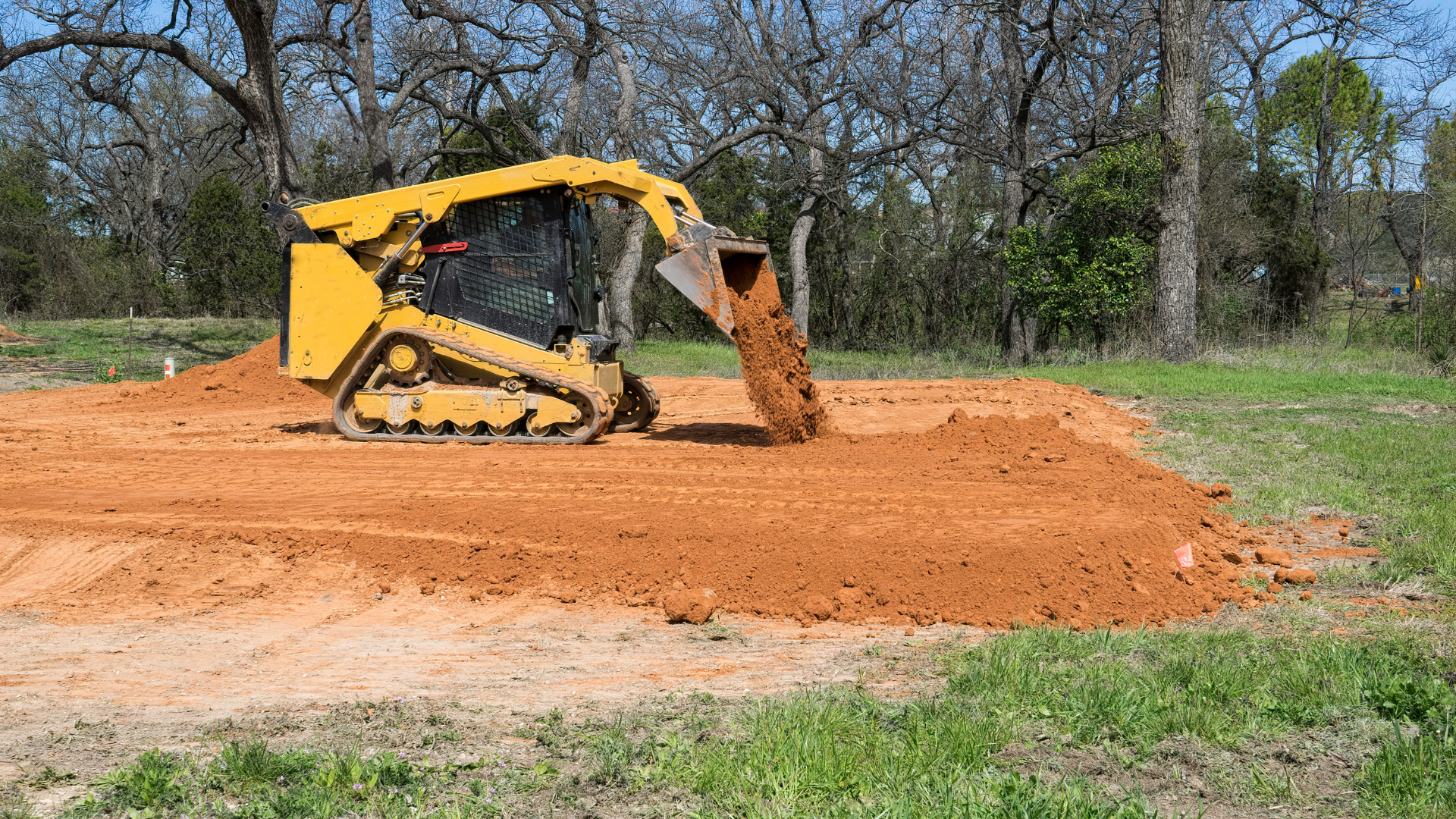 Yellow excavator building a stone retaining wall at a forested construction site