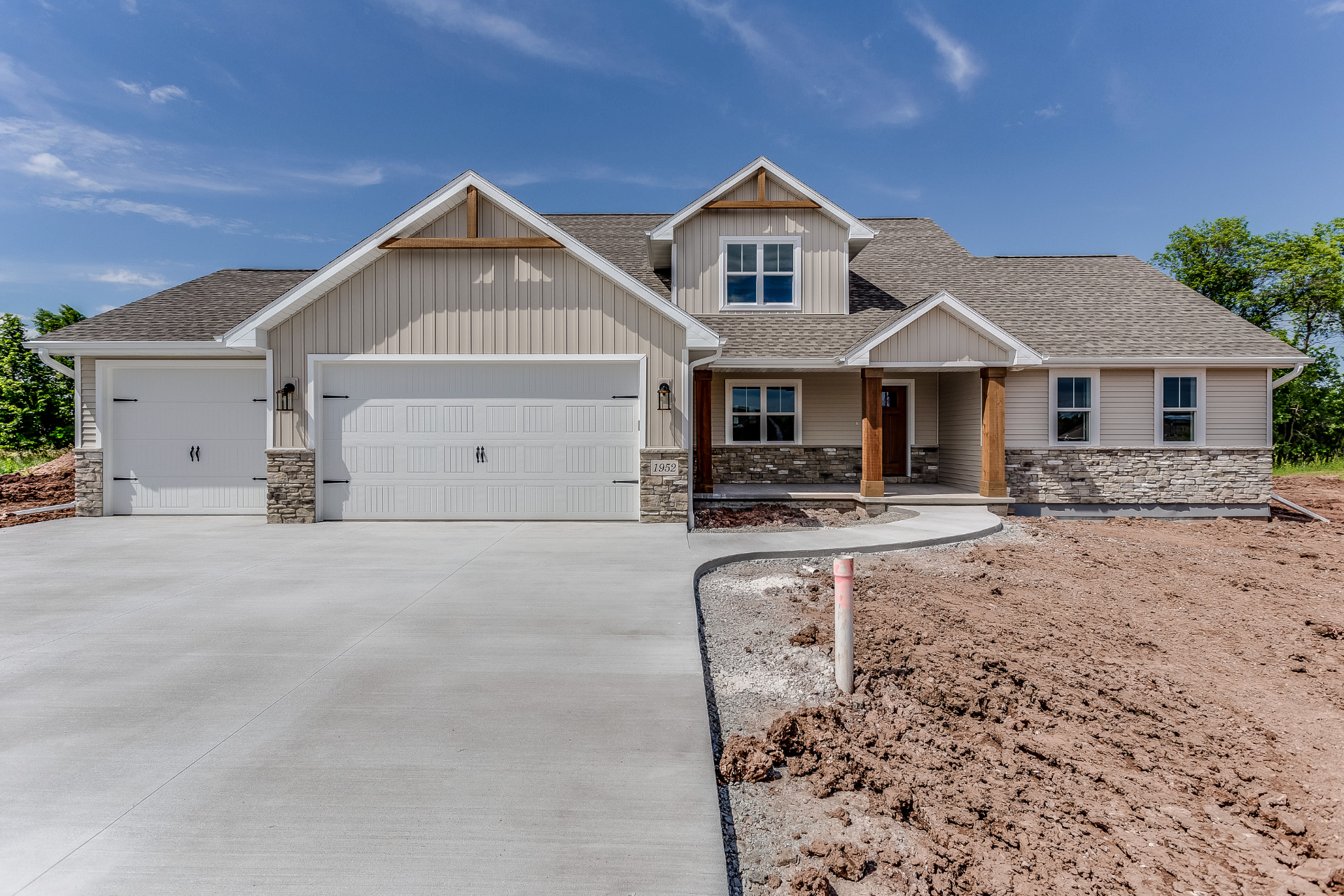 New suburban house with three-car garage and concrete driveway under a blue sky