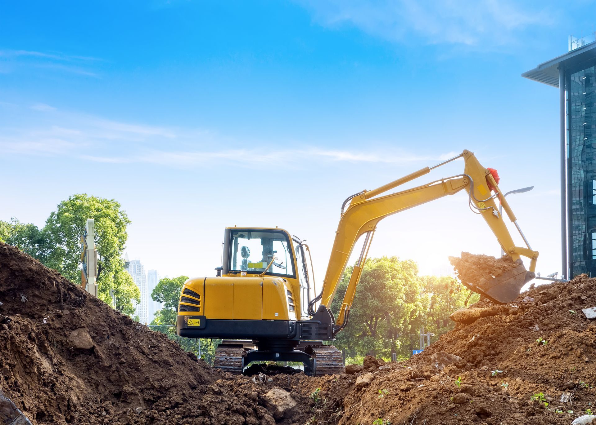 Yellow excavator digging dirt on a construction site under a blue sky