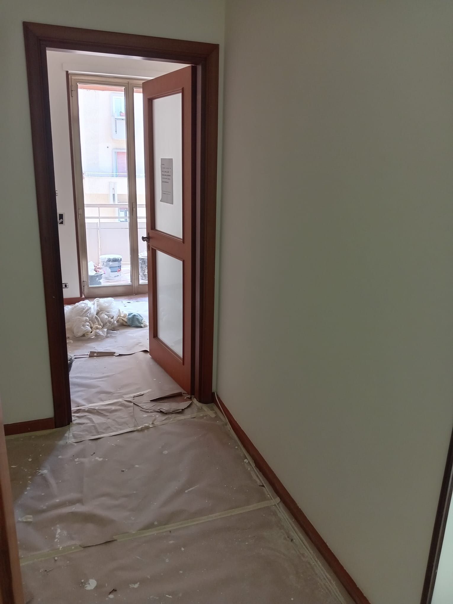 Un corridoio con una porta aperta e una finestra.