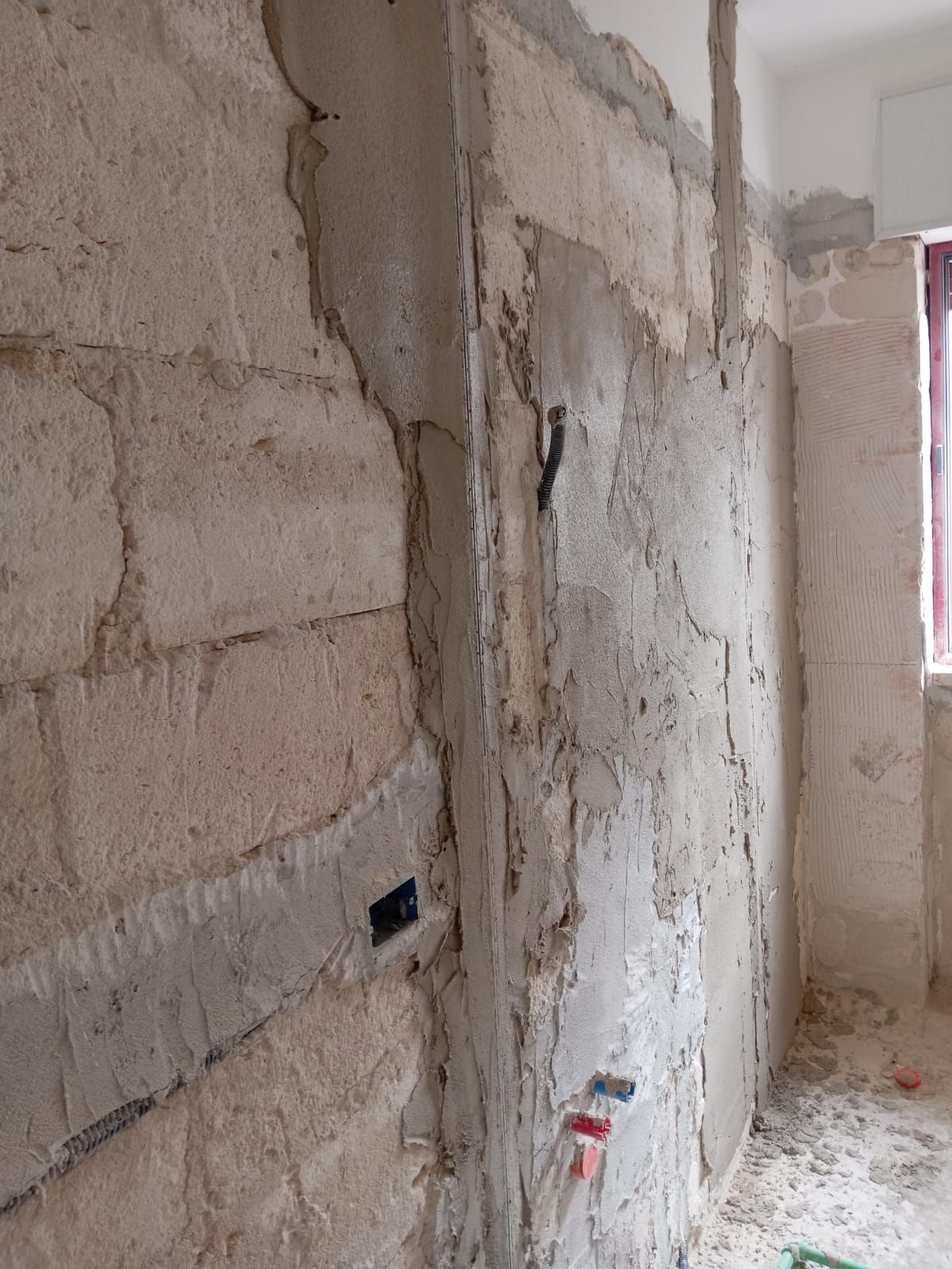 Una stanza con un muro di mattoni e una finestra.