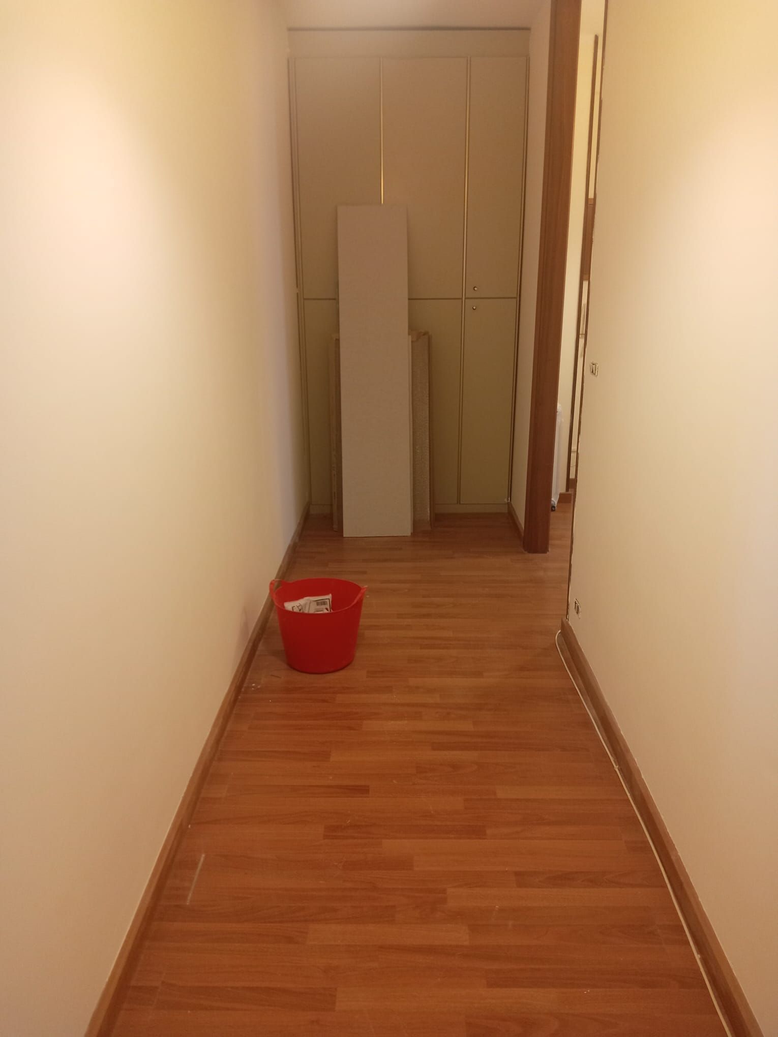 Un lungo corridoio con un secchio rosso sul pavimento.