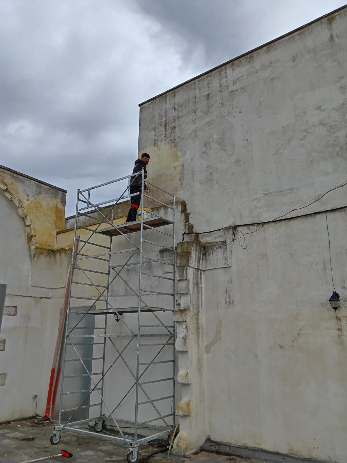 Un uomo è in piedi su un'impalcatura sul lato di un edificio.