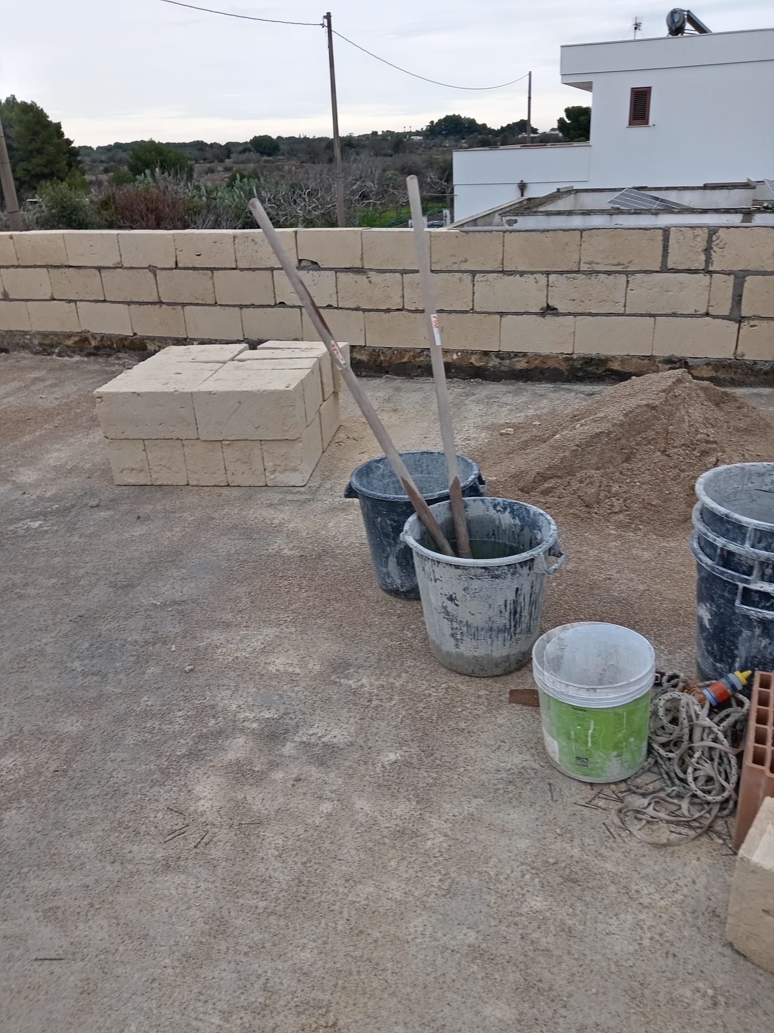 Secchi di cemento sono appoggiati a terra davanti a un muro di mattoni.