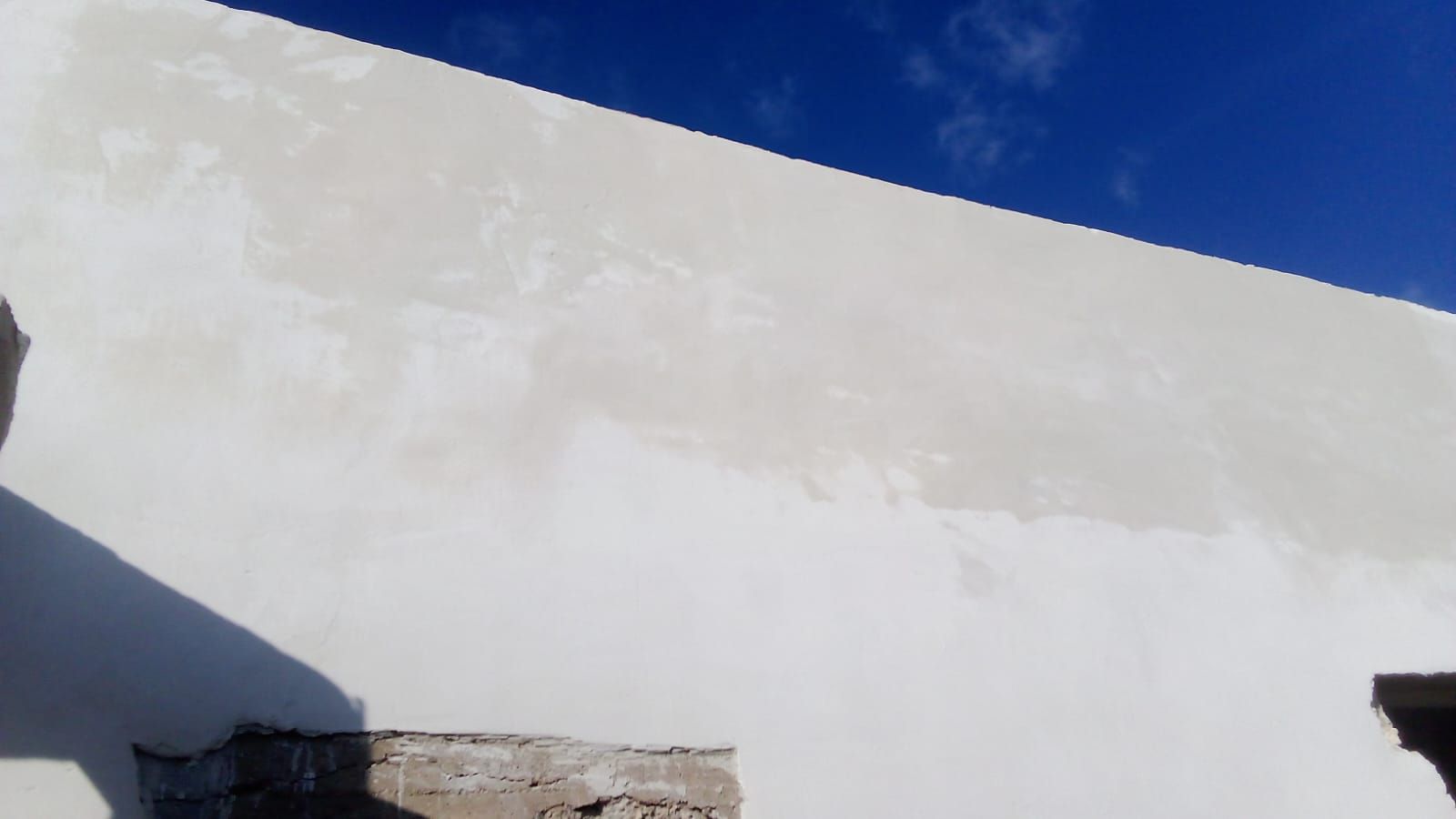 Un muro bianco con un cielo azzurro sullo sfondo.