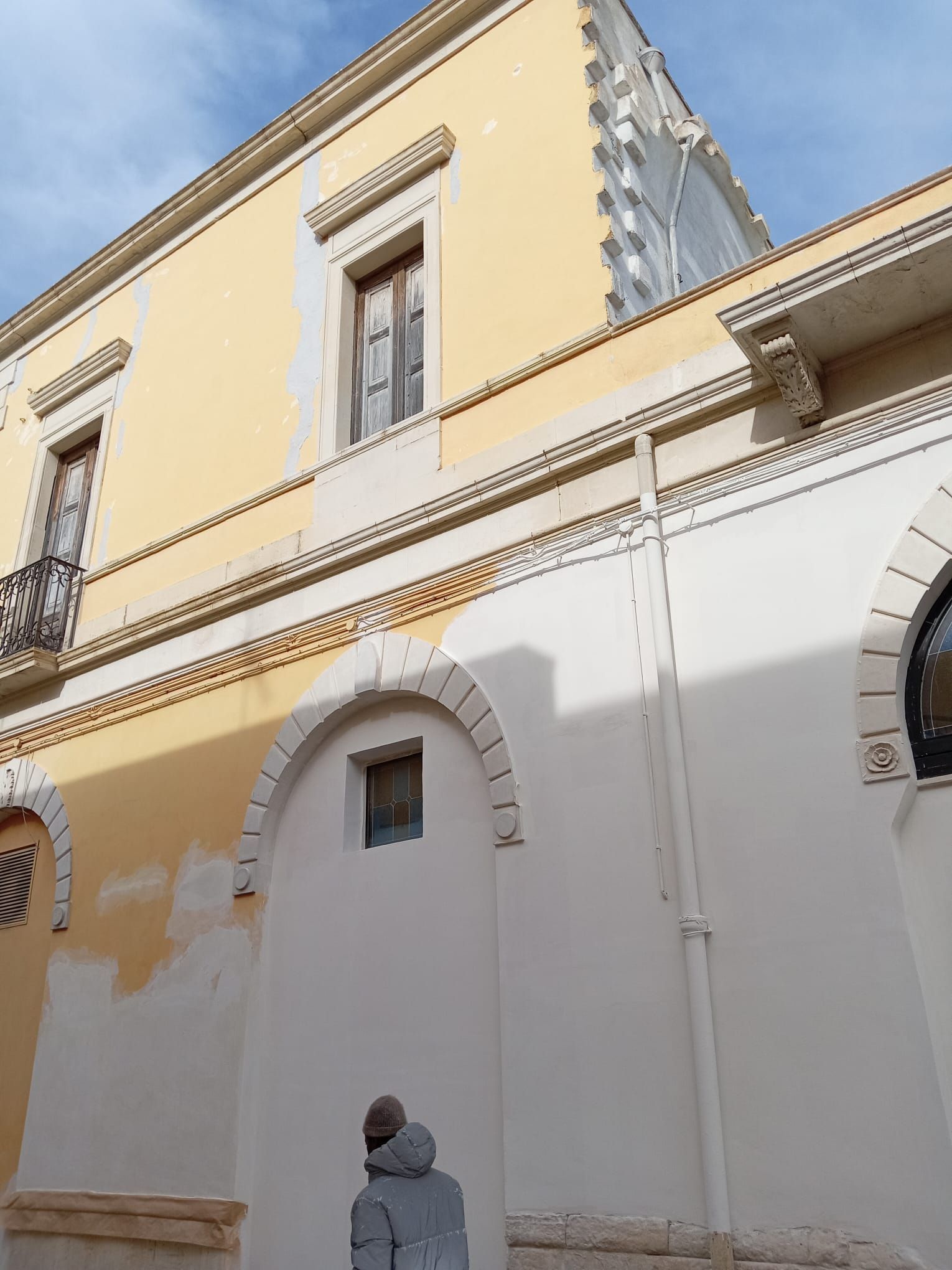 Un edificio giallo e bianco con una statua di fronte.