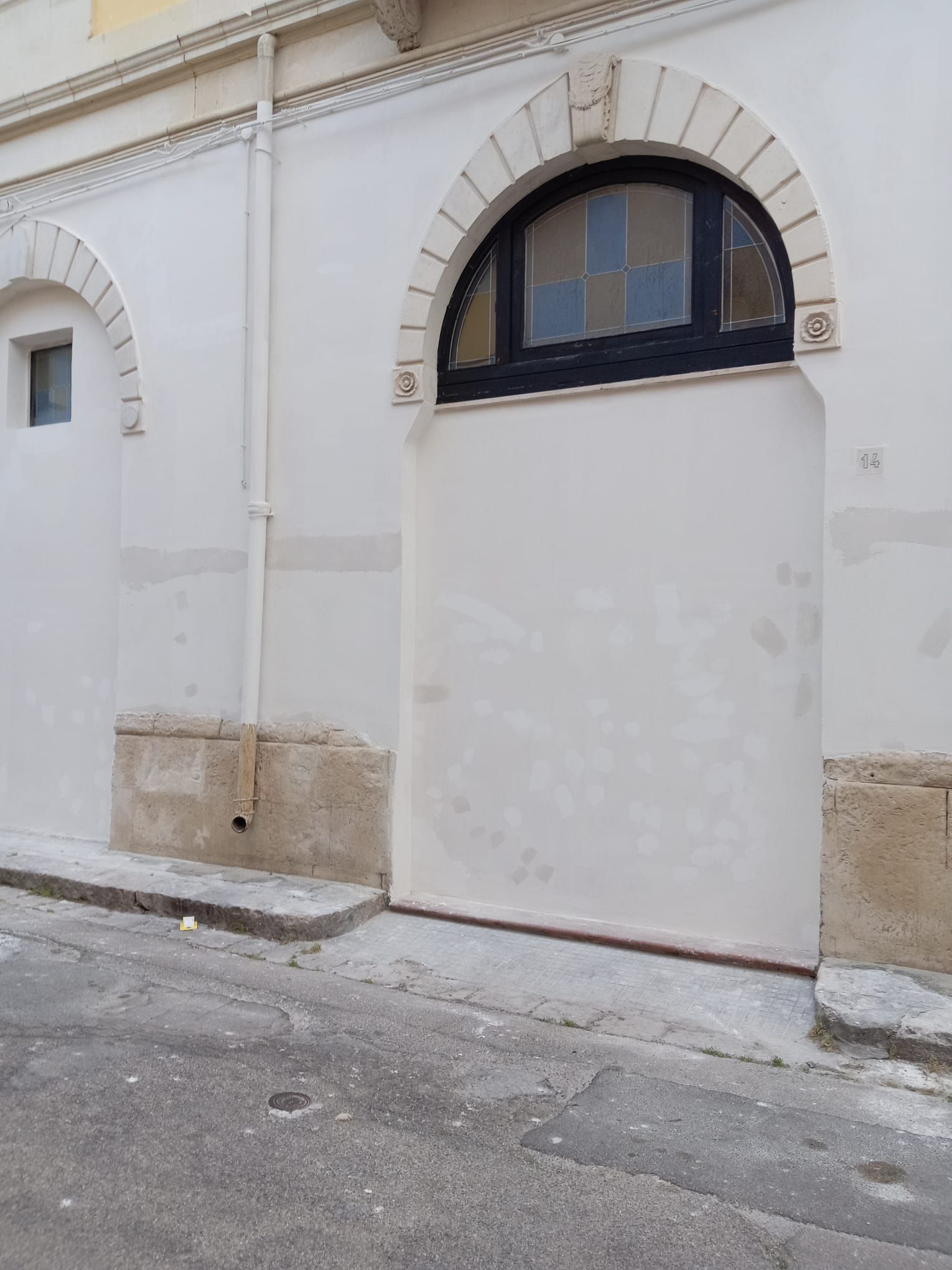 Un edificio bianco con un arco nero e una finestra