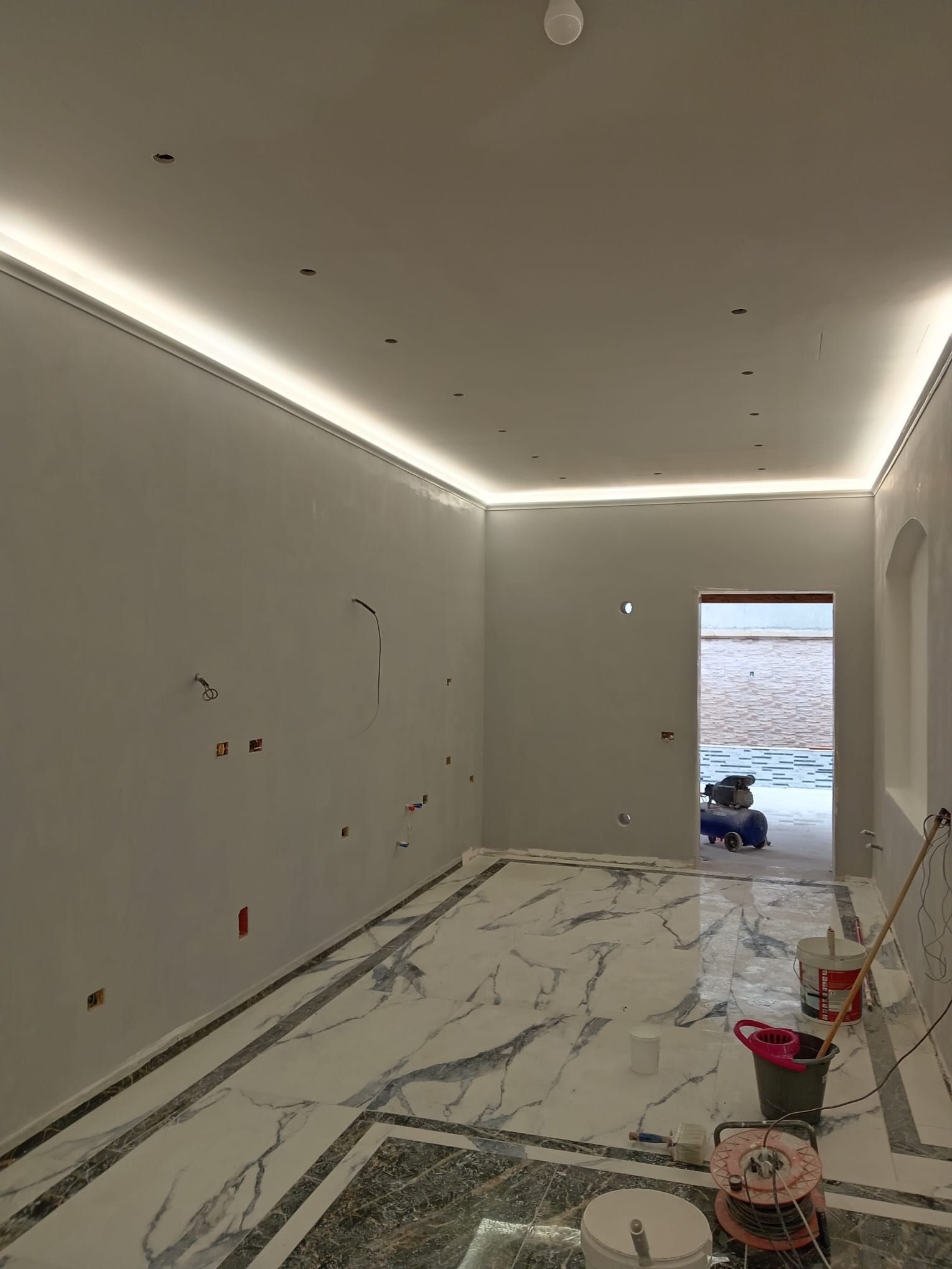 Una stanza con pavimento in marmo e soffitto in fase di ristrutturazione.