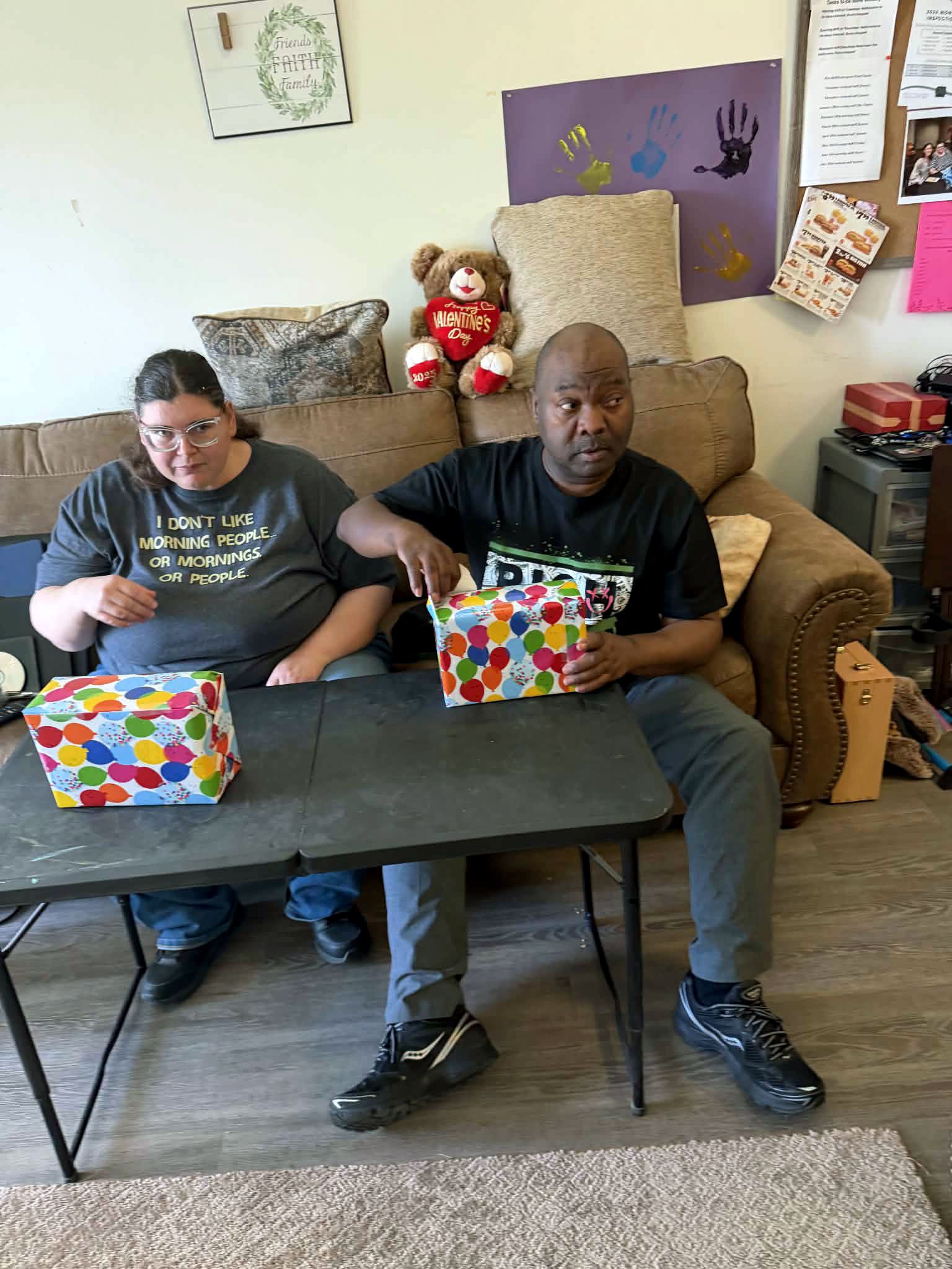 Mike opening a present while Tiffany watches.