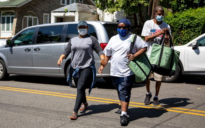 Chalonda Day, 38, who works in direct support at JEVS Human Services, left, Charlie Flowe, 29, center, and Julian Jordan, 28, right, approach a JEVS group home to deliver donated food from Chick-fil-A and Wawa. (Tyger Williams/The Philadelphia Inquirer/TNS)