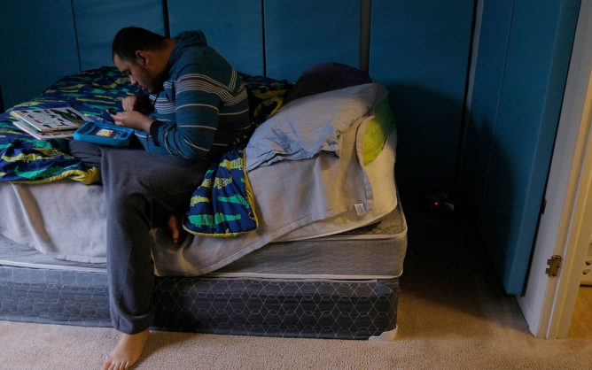 Kristopher Conley plays on a tablet in his bedroom at the home he shares with his twin brother near Columbus, Ohio. Both brothers have severe autism and need 24-hour care. (Courtney Hergesheimer/The Columbus Dispatch/TNS)