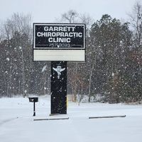 A sign for a chiropractic clinic is covered in snow.