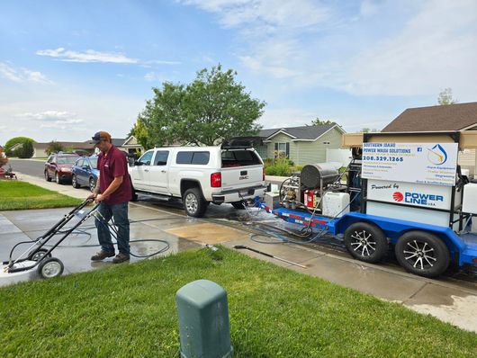 A man is cleaning a driveway with a pressure washer.