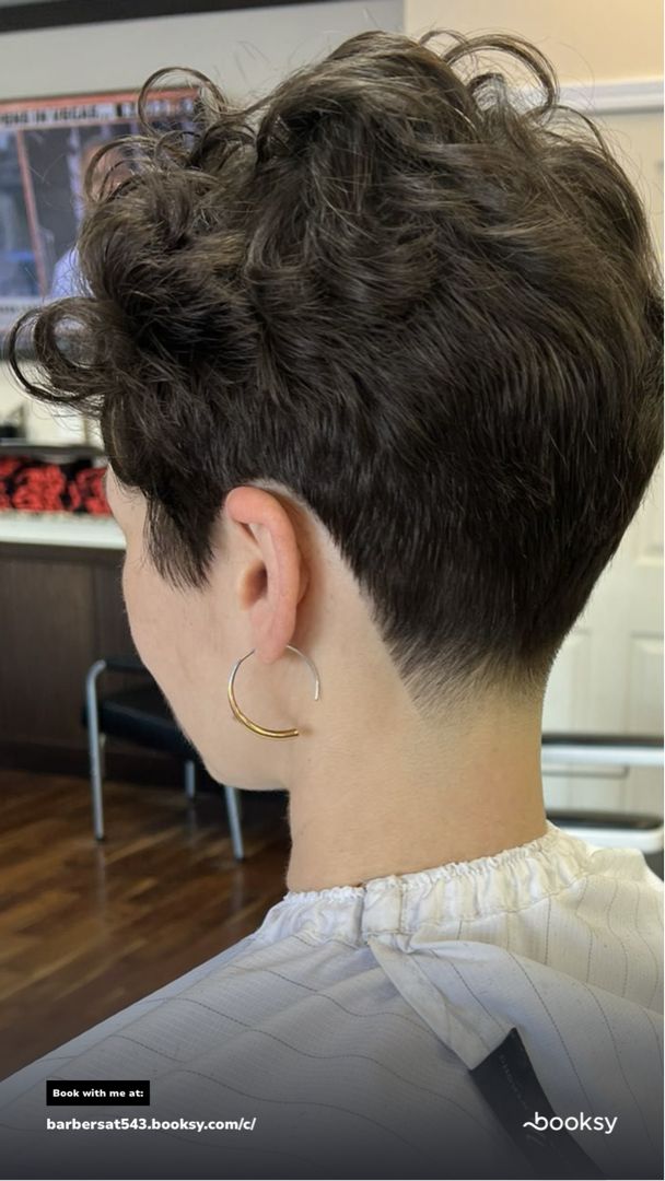 Person with short, dark, textured hair; shaved neckline; wearing gold hoop earring.