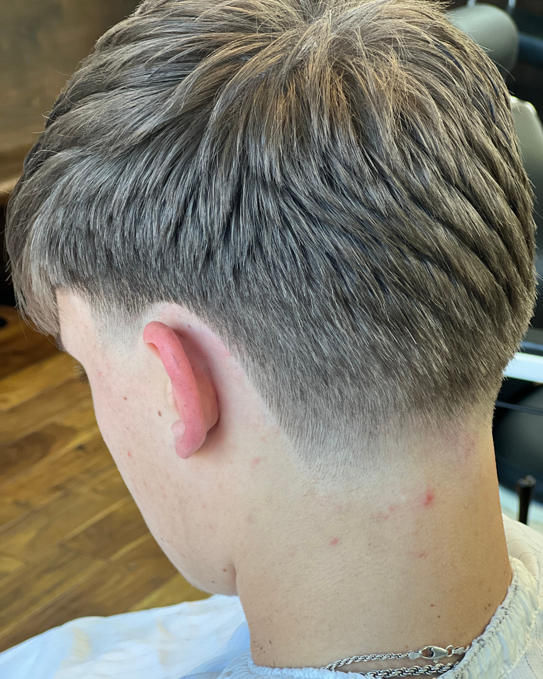 Close-up of a person's neck and ear, showcasing a tapered haircut with faded sides.