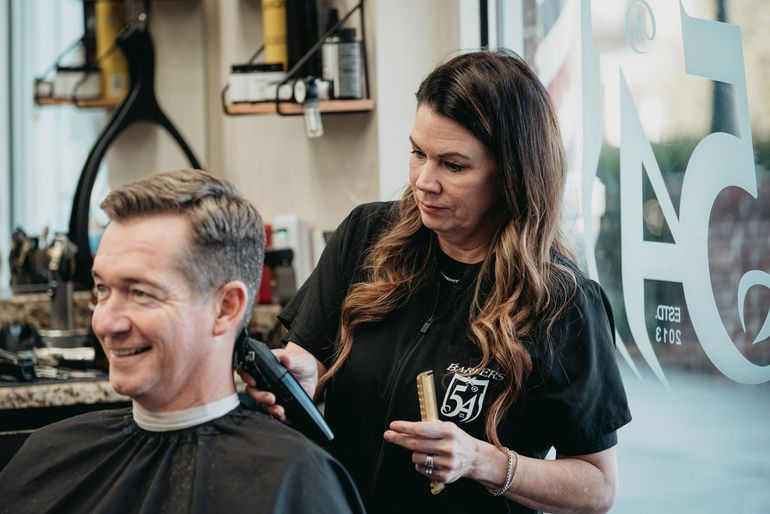 A barber giving a customer a haircut in a barbershop.