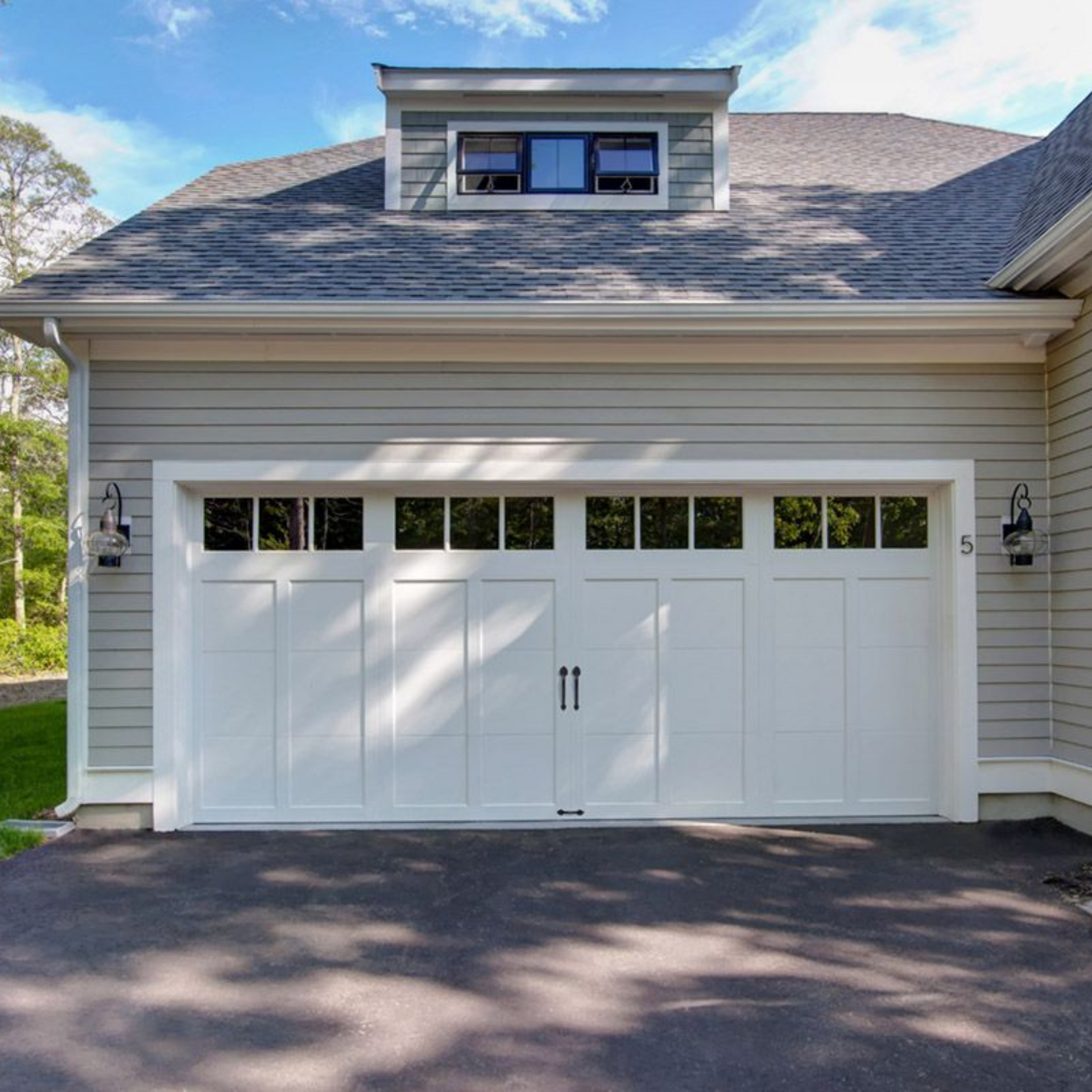 A large white garage door is sitting in front of a house.