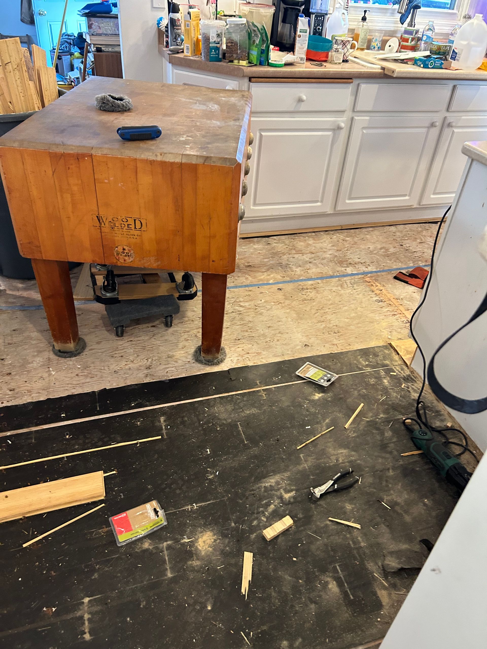 Butcher block table and cabinets in a kitchen undergoing renovation with debris on the floor.