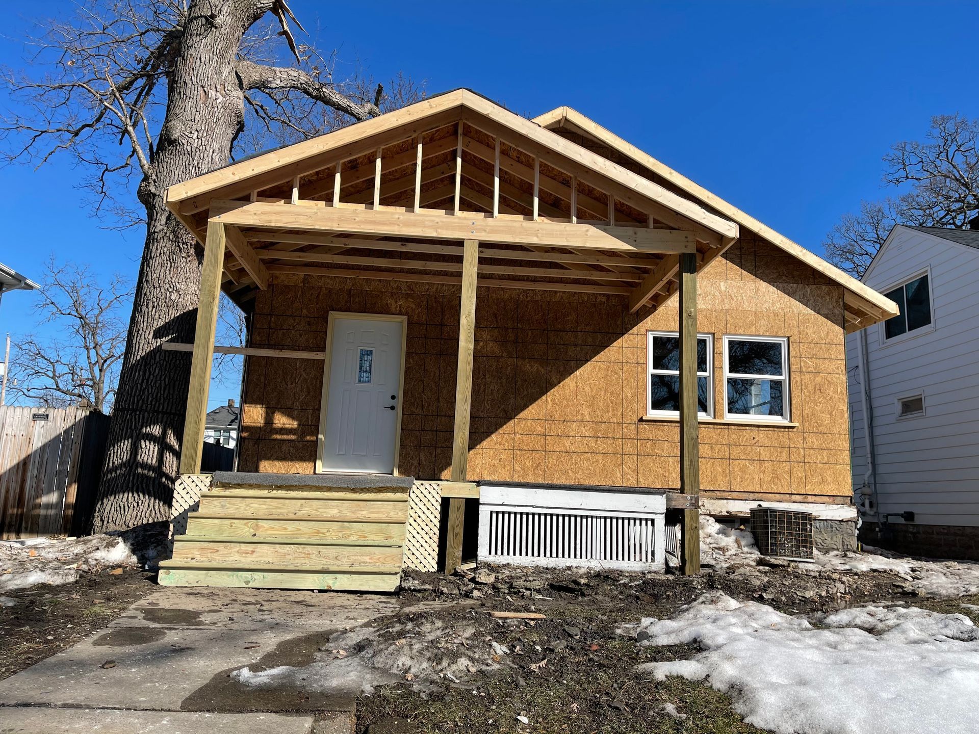 House under construction with porch and snow on the ground.
