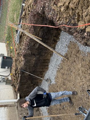 Person doing plank next to trench with gravel, wires, and soil.