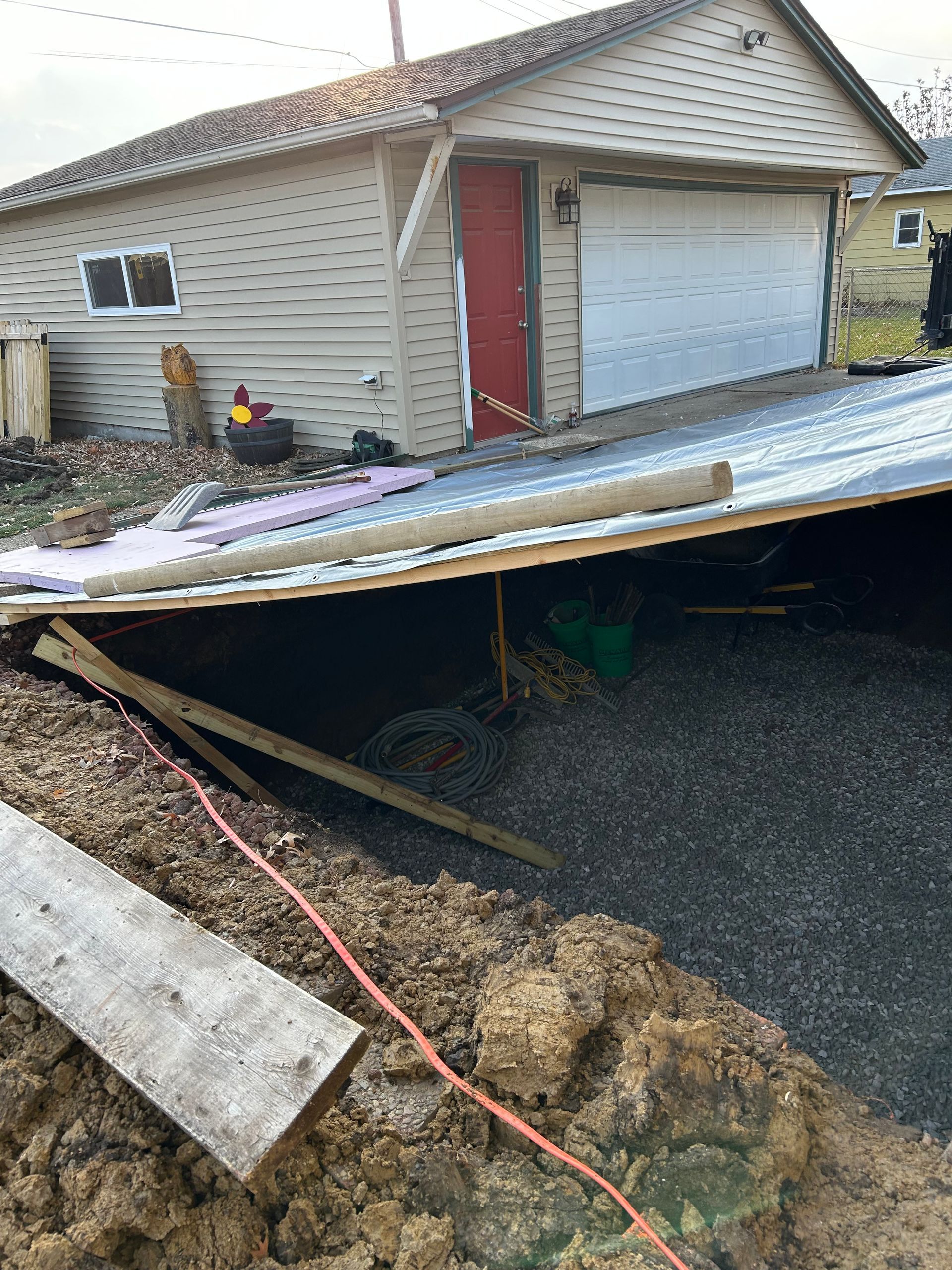Garage with a collapsed roof, debris, and gravel.
