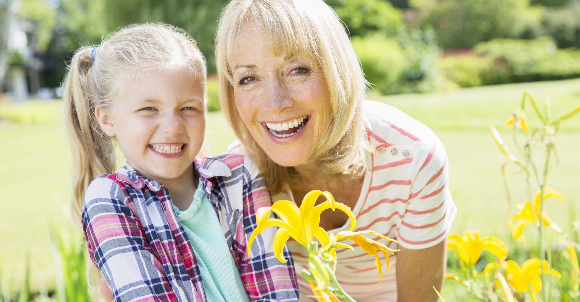 middle aged woman and young female child picking flowers together and smiling