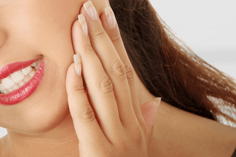 woman holding the side of her jaw in pain
