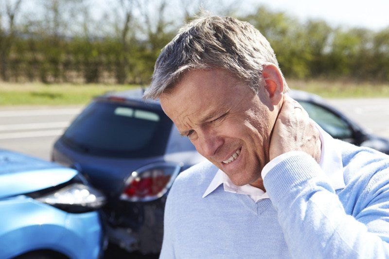 Gentleman holding neck in front of a road traffic accident