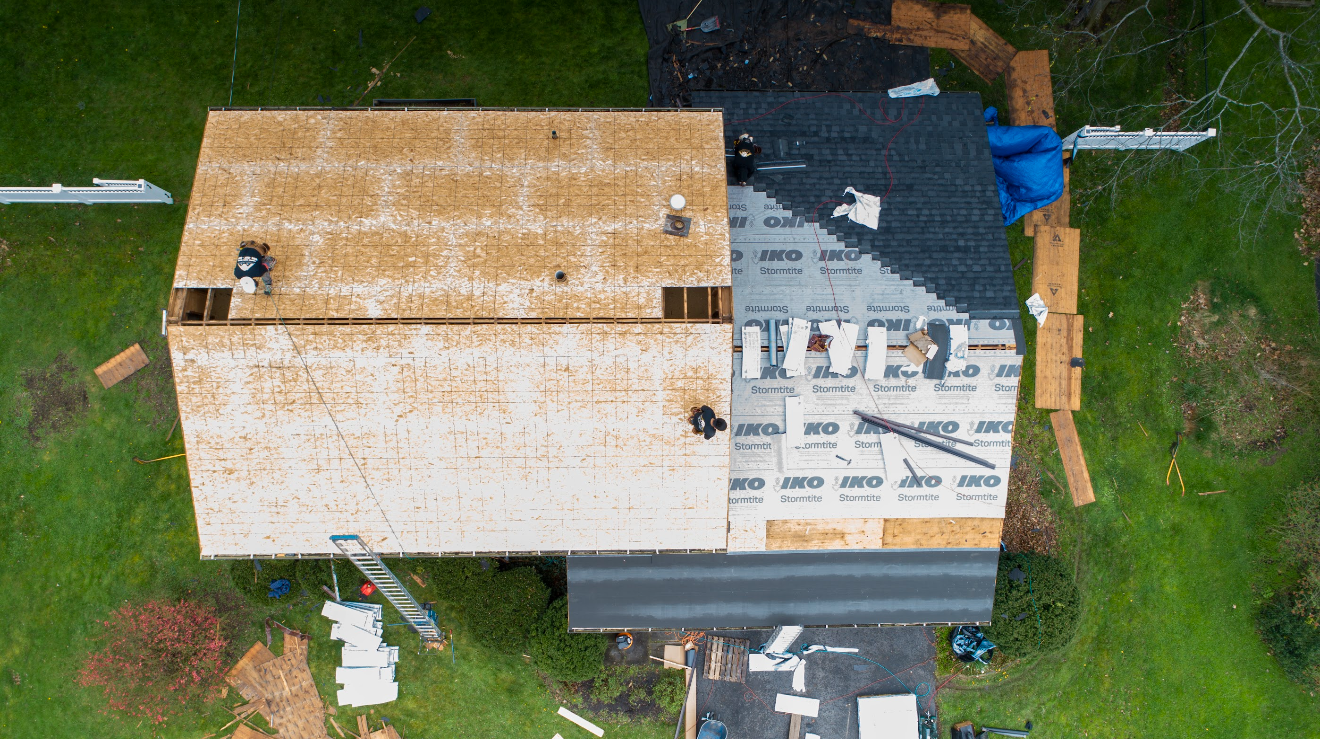 An aerial view of a house under construction with a roof being installed.