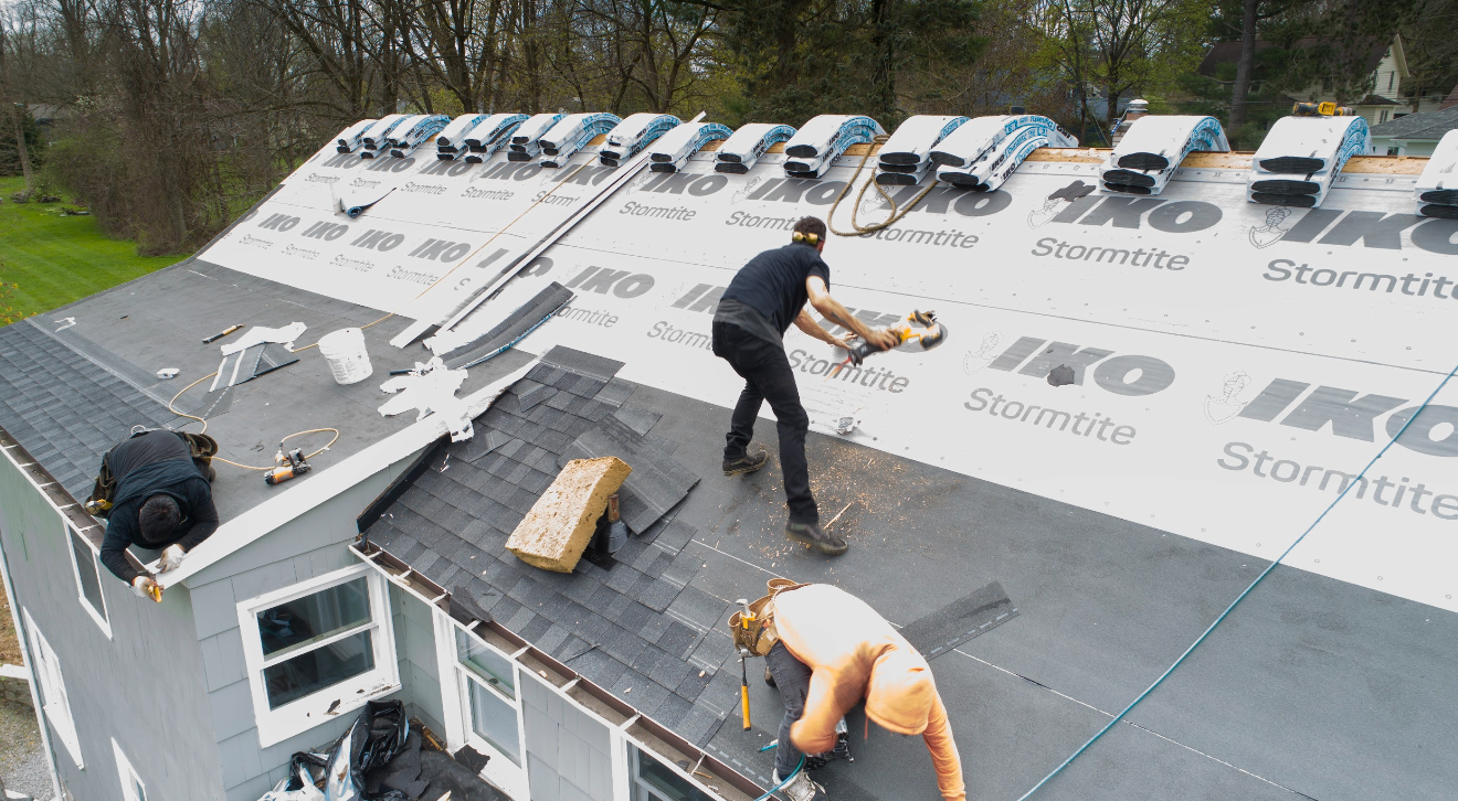 A group of men are working on the roof of a house.