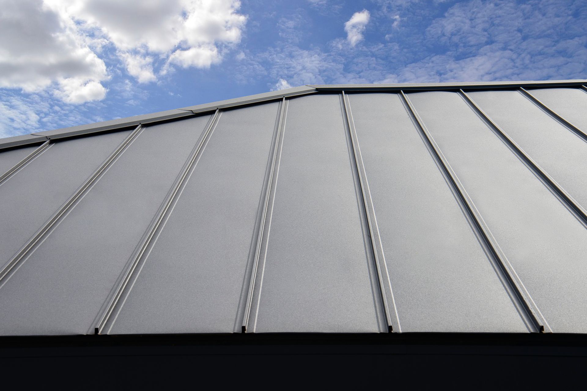 A close up of a metal roof with a blue sky in the background.