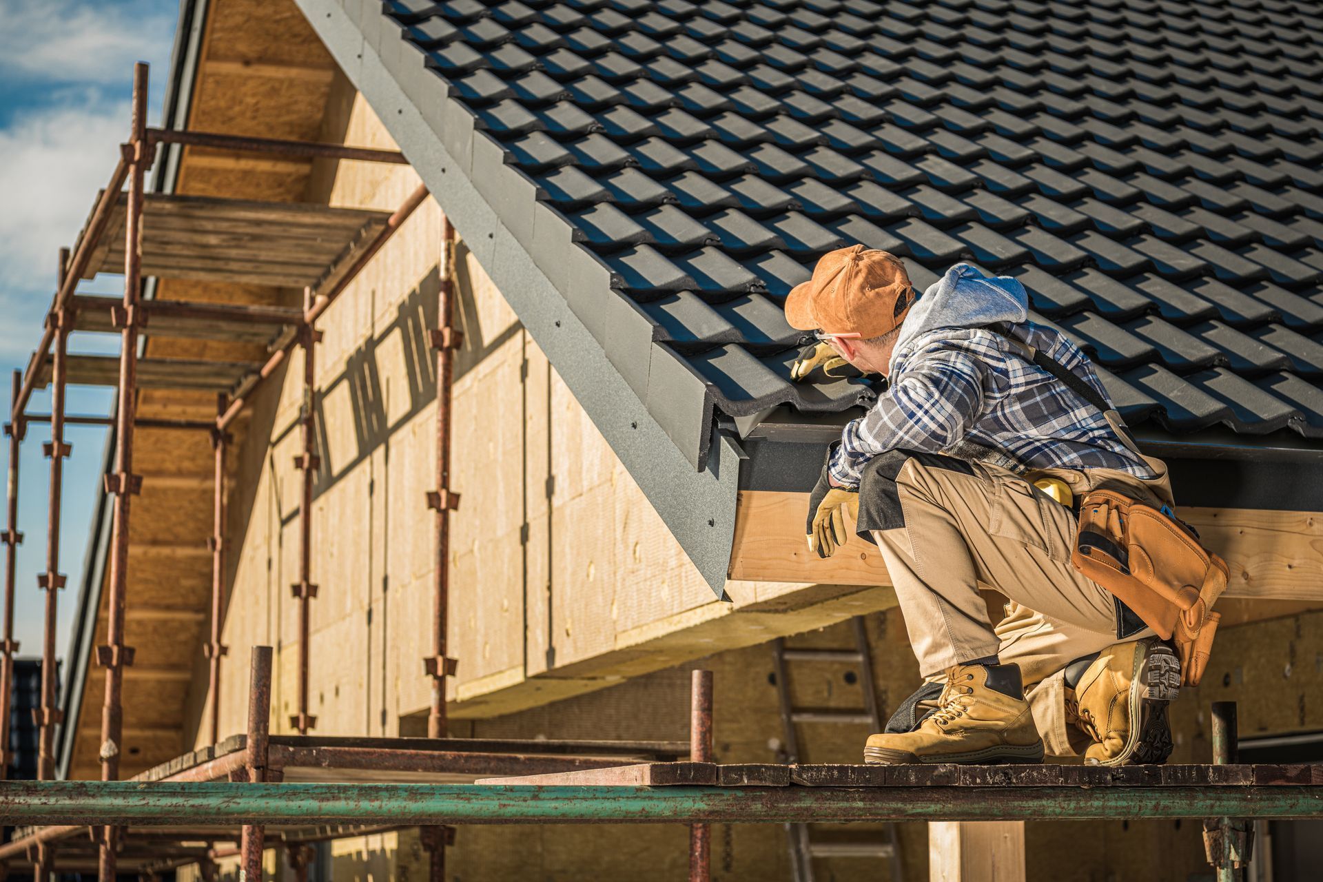 A construction worker is working on the roof of a house under construction.