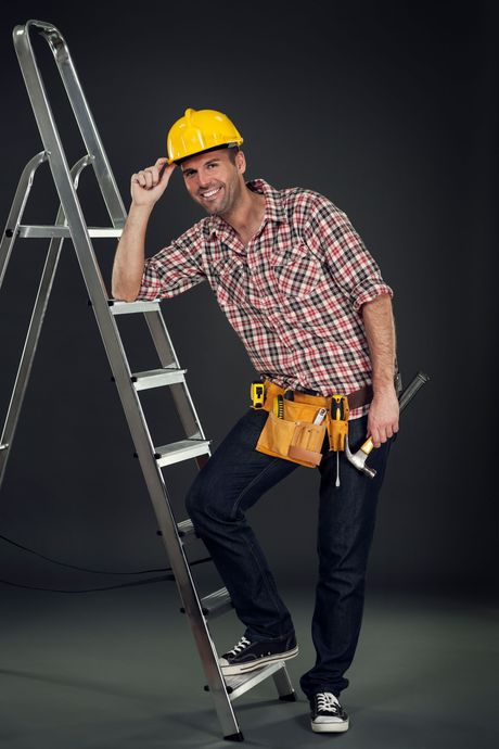 A man wearing a hard hat is standing on a ladder.