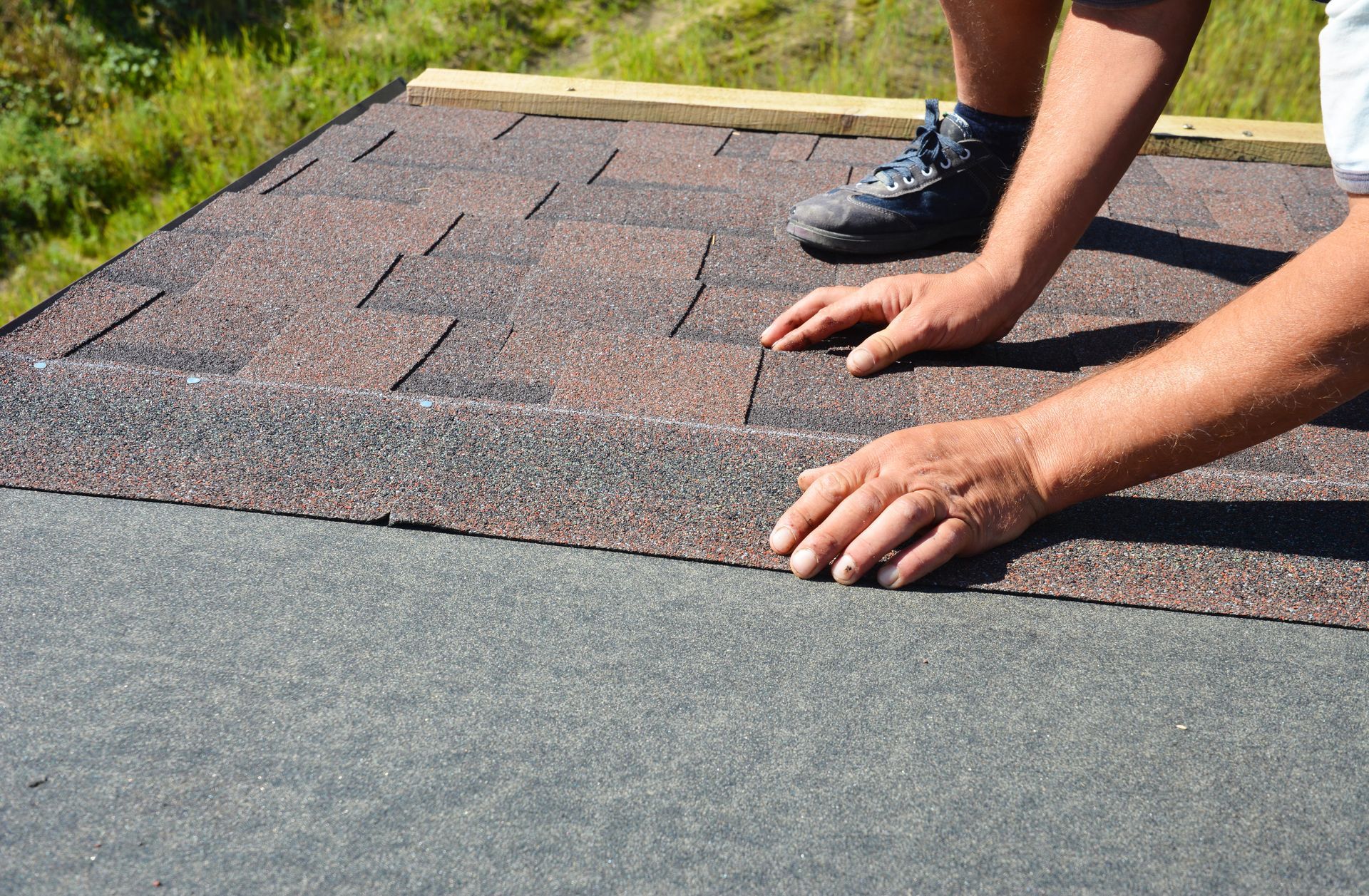 A person is laying shingles on a roof.