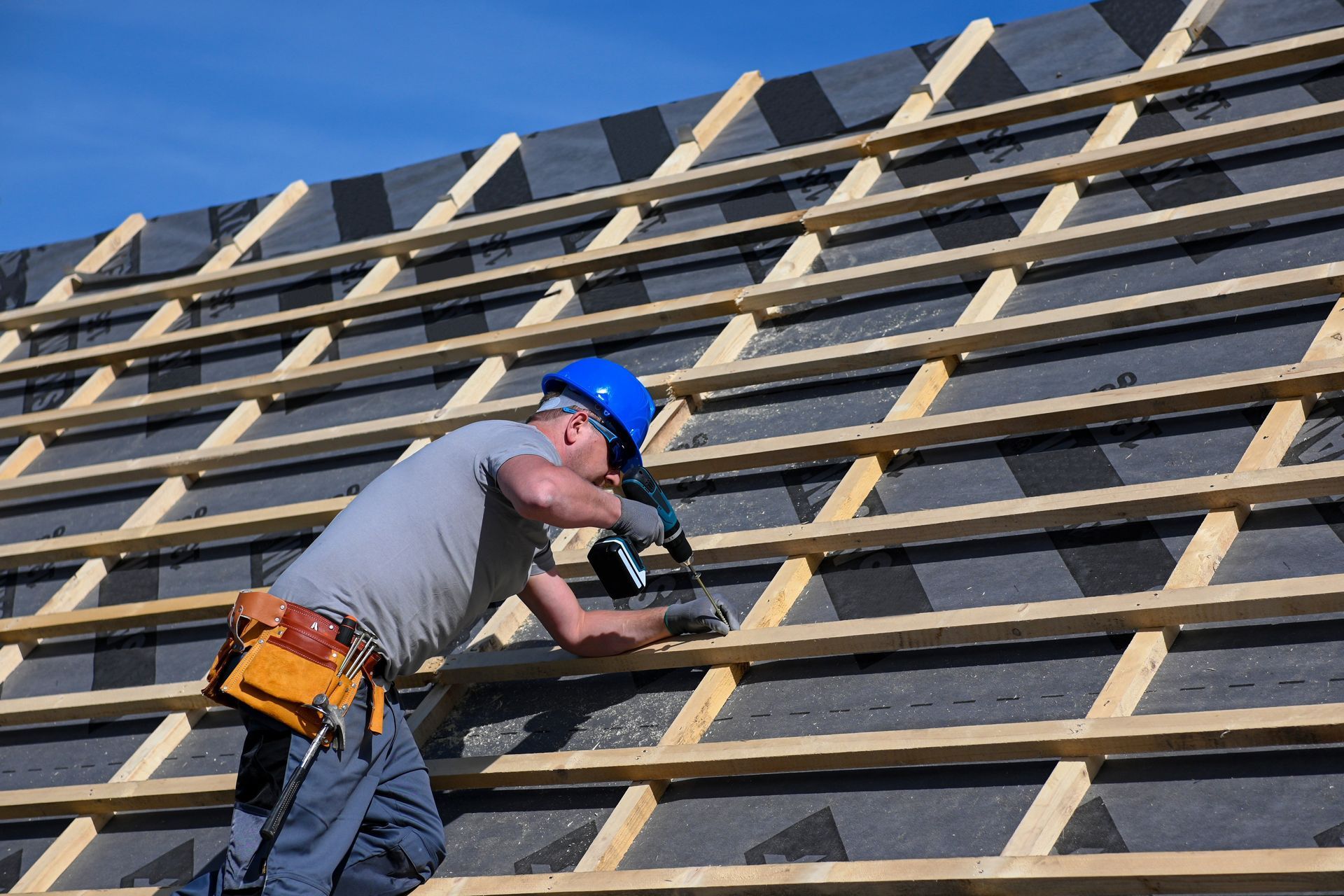 A man is working on a roof with a drill.