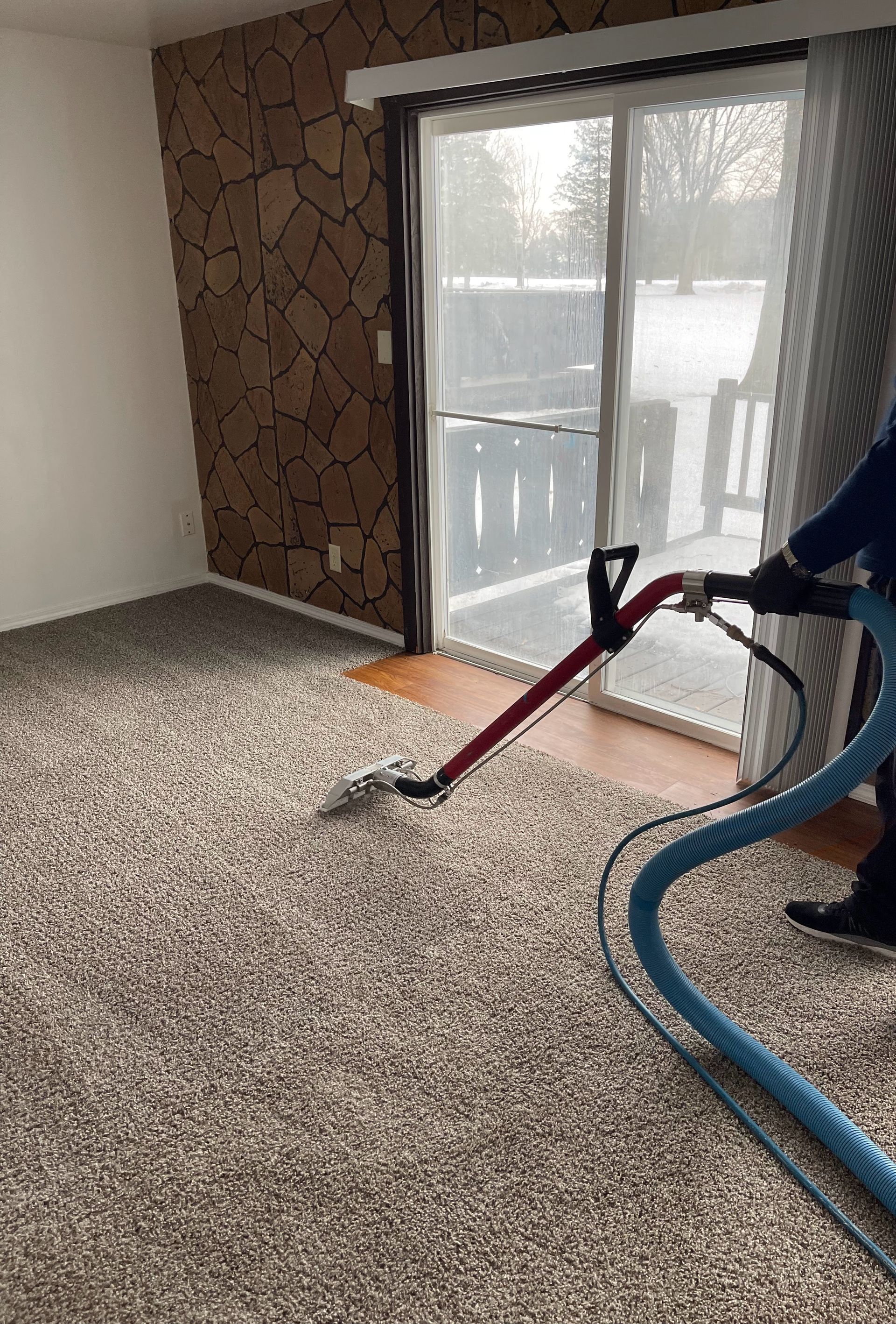 A person is using a vacuum cleaner to clean a carpet in a living room.