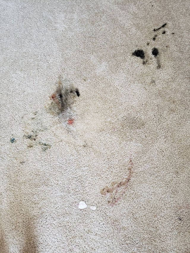 A close up of a dirty carpet with stains on it.